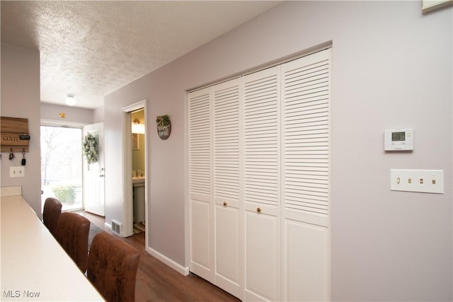 dining space with baseboards, a textured ceiling, and wood finished floors