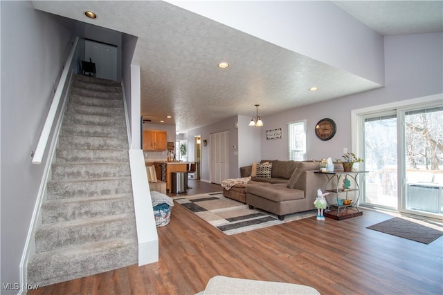 living area with light wood finished floors, recessed lighting, a textured ceiling, and stairs