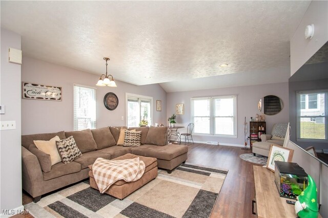 living area with baseboards, vaulted ceiling, light wood-style floors, a textured ceiling, and a notable chandelier