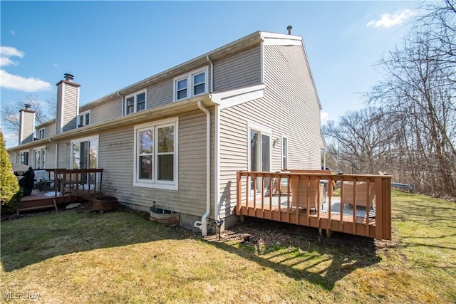 back of property with a deck and a lawn