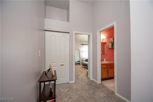 hall with baseboards and light carpet