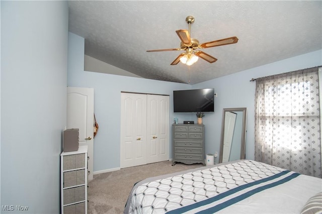 carpeted bedroom with lofted ceiling, a ceiling fan, a closet, and a textured ceiling