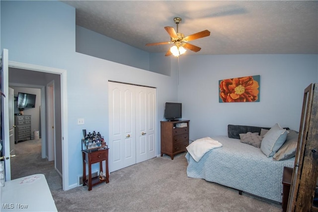 carpeted bedroom with a closet, high vaulted ceiling, ceiling fan, and a textured ceiling