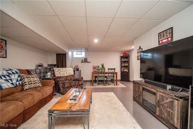 living room with a paneled ceiling and concrete flooring