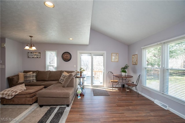 living area featuring lofted ceiling, wood finished floors, visible vents, and a healthy amount of sunlight