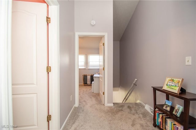 corridor featuring an upstairs landing, light colored carpet, and baseboards