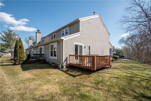 back of house with a yard, a chimney, and a deck