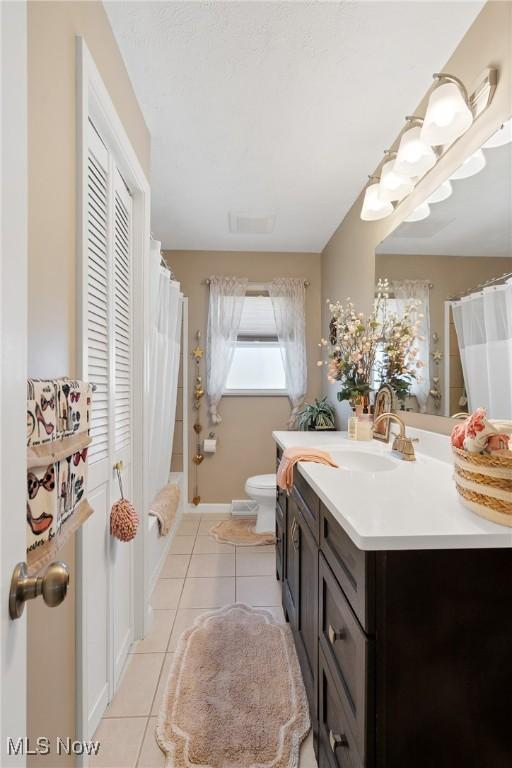 full bathroom with curtained shower, baseboards, toilet, tile patterned floors, and vanity