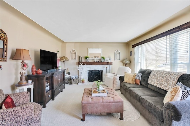 living room featuring a fireplace with raised hearth and light carpet