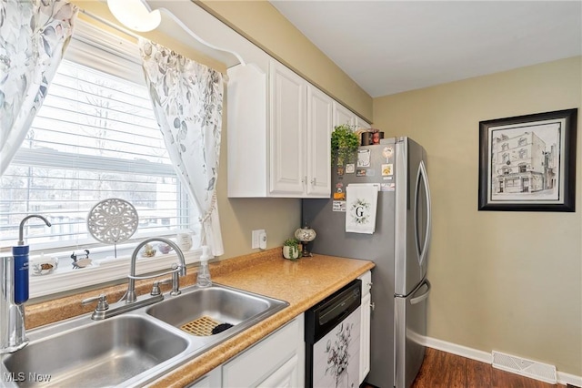 kitchen with visible vents, a sink, white cabinetry, baseboards, and dishwasher