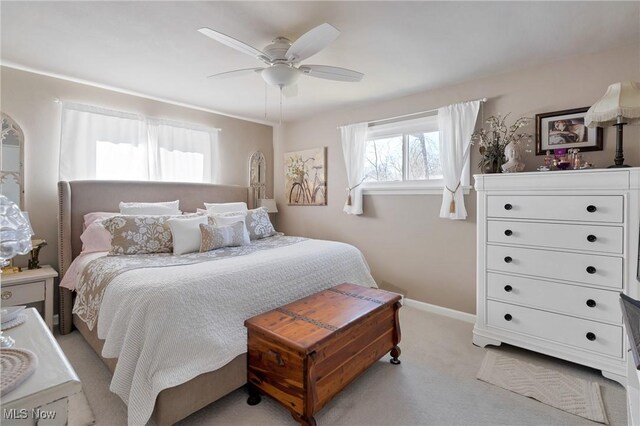 bedroom with a ceiling fan, baseboards, and light carpet