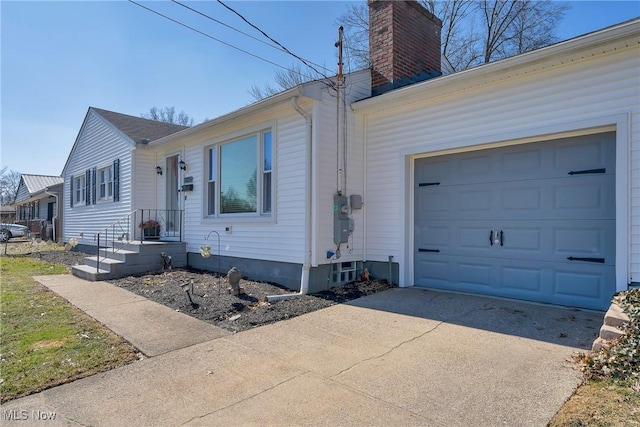 view of front facade featuring driveway, a chimney, and a garage