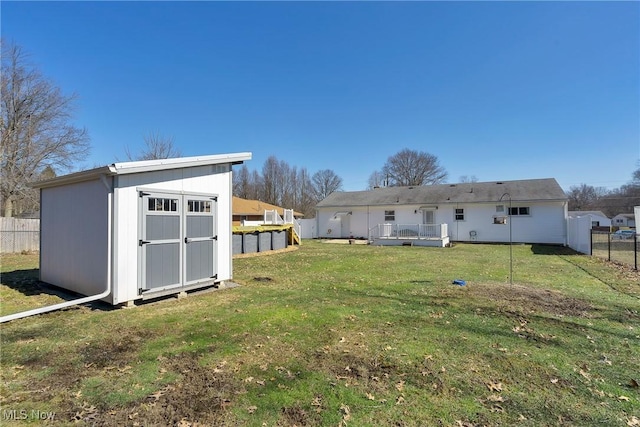 rear view of property with a fenced backyard, a shed, a yard, an outdoor structure, and a wooden deck