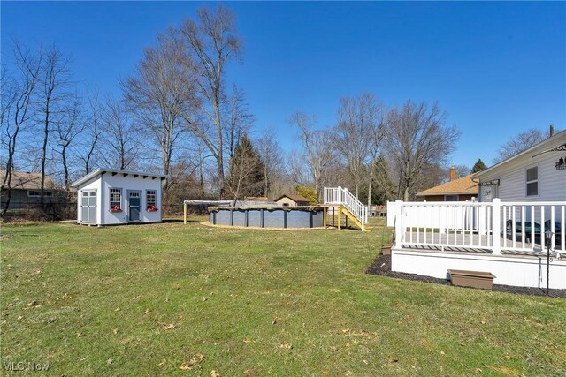 view of yard with a covered pool, a wooden deck, a storage shed, and an outdoor structure