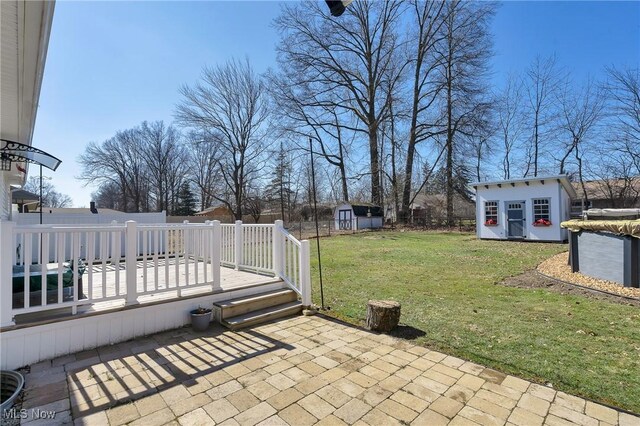 view of patio / terrace featuring a deck, an outdoor structure, a storage unit, and a fenced backyard