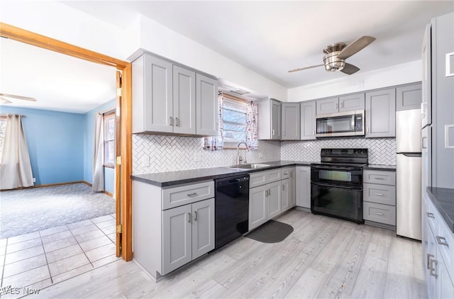 kitchen with ceiling fan, a sink, black appliances, gray cabinetry, and dark countertops