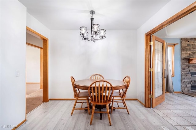 dining room featuring a chandelier, light wood-style flooring, and baseboards