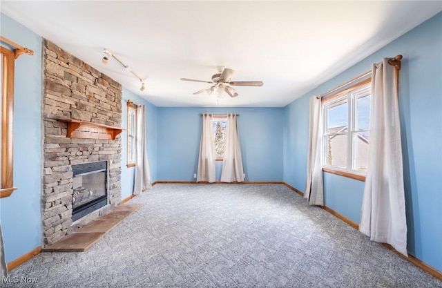 unfurnished living room with carpet flooring, baseboards, a ceiling fan, and a fireplace