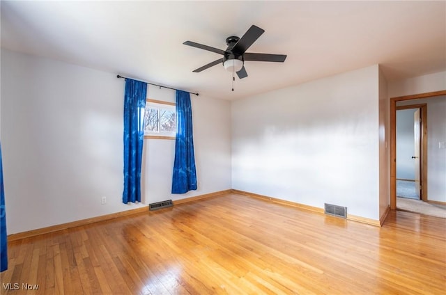 spare room featuring visible vents, a ceiling fan, baseboards, and hardwood / wood-style flooring