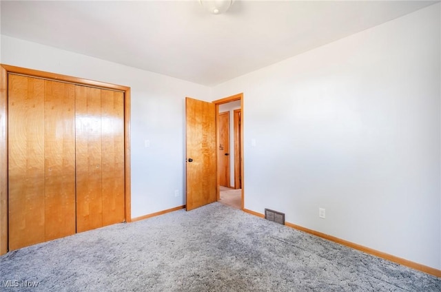 unfurnished bedroom with carpet flooring, baseboards, visible vents, and a closet