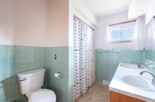 full bathroom featuring a shower with shower curtain, tile walls, toilet, and a sink