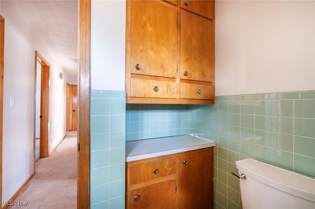 bathroom featuring toilet and tile walls