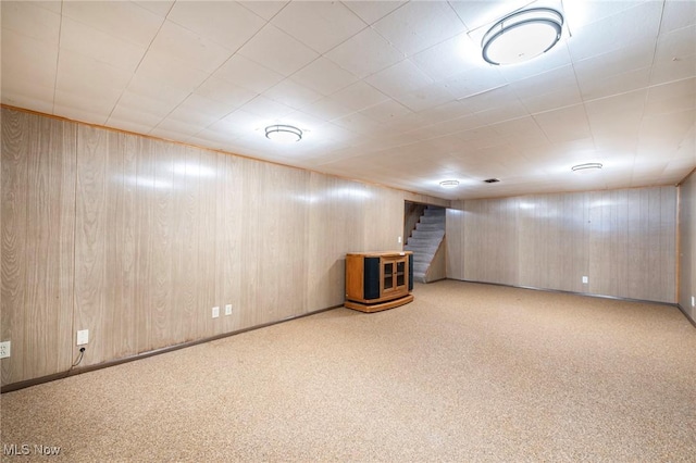 finished below grade area featuring stairs, wooden walls, carpet, and baseboards