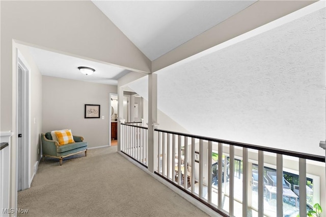 hall featuring baseboards, carpet, and vaulted ceiling