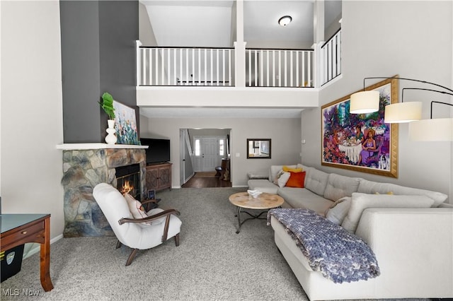 living room featuring baseboards, a stone fireplace, and a towering ceiling