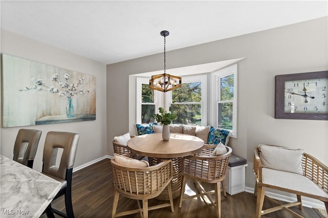 dining area featuring a chandelier, breakfast area, dark wood-type flooring, and baseboards