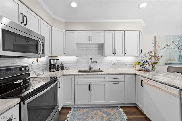 kitchen with crown molding, dark wood-type flooring, white cabinets, stainless steel appliances, and a sink