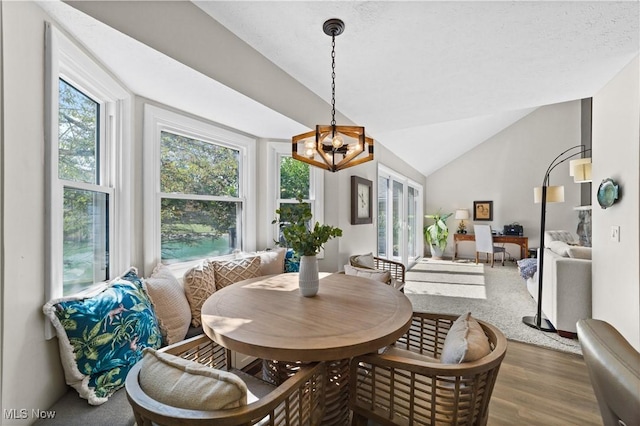 dining room with lofted ceiling, a notable chandelier, and wood finished floors