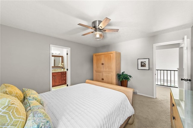 bedroom featuring light colored carpet, baseboards, ensuite bathroom, and ceiling fan