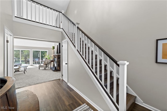 stairs with baseboards, a high ceiling, and wood finished floors