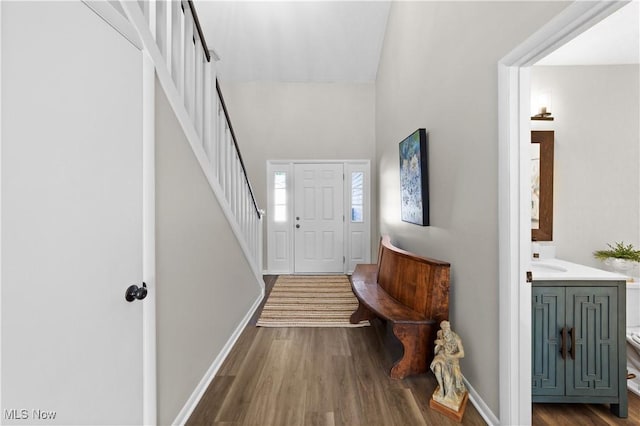 foyer entrance with baseboards, wood finished floors, and stairs