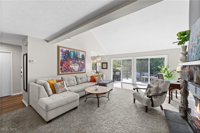 living room with a fireplace, a textured ceiling, and lofted ceiling with beams