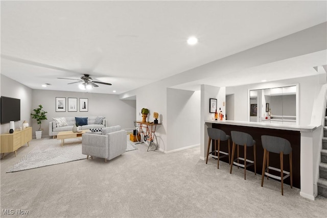 living area featuring recessed lighting, light colored carpet, a bar, and baseboards