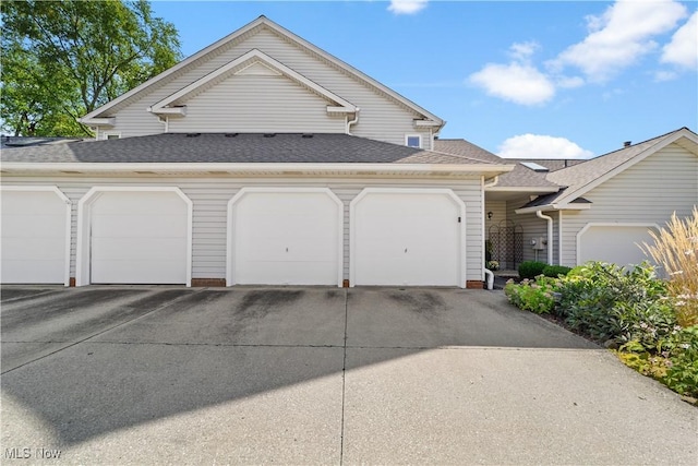 view of front of home featuring driveway, a shingled roof, and an attached garage