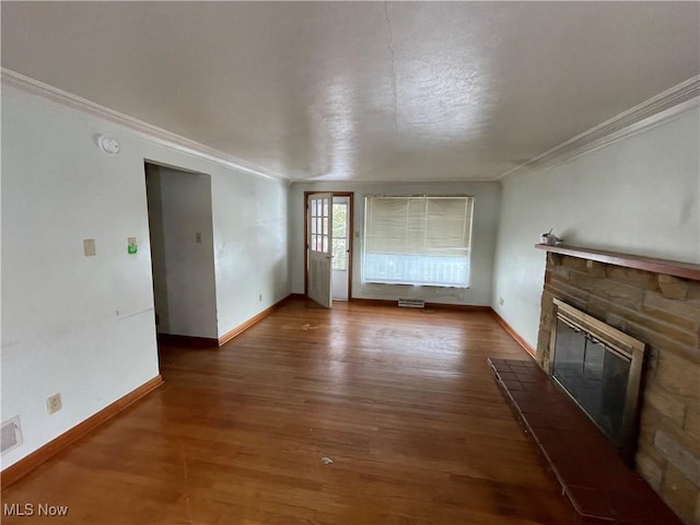 unfurnished living room featuring wood finished floors, baseboards, visible vents, a stone fireplace, and crown molding