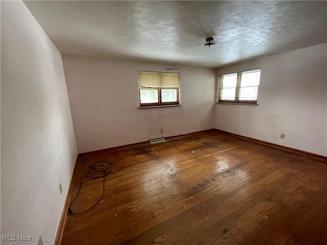 empty room with visible vents, baseboards, and hardwood / wood-style floors