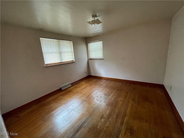 spare room with visible vents, baseboards, and wood finished floors