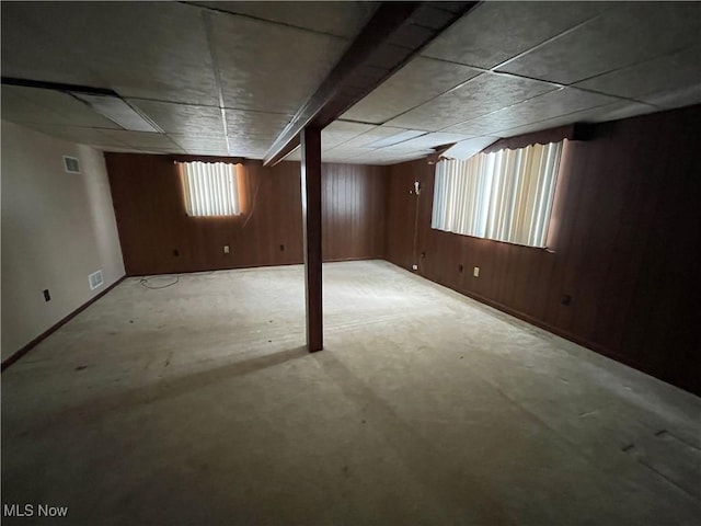 below grade area featuring carpet flooring, visible vents, and wood walls