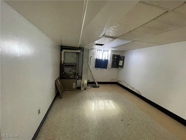 basement featuring electric panel, heating unit, and baseboards