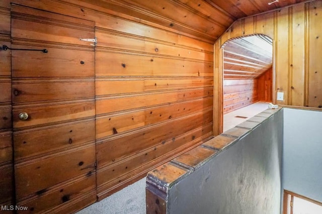 corridor featuring carpet floors, a sauna, vaulted ceiling, wood ceiling, and wood walls