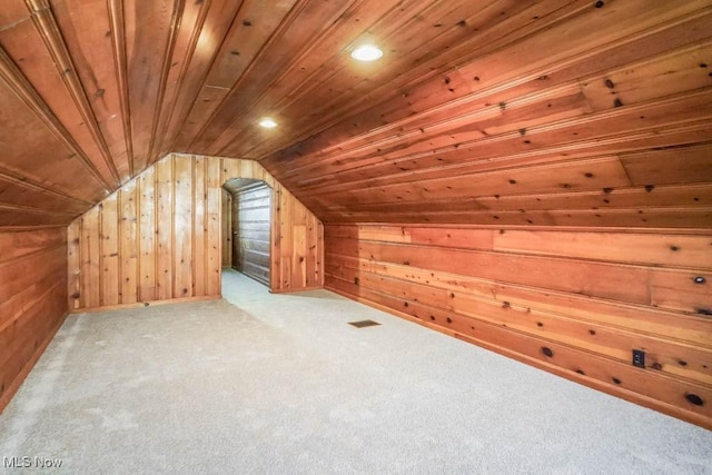 bonus room featuring visible vents, vaulted ceiling, wood ceiling, wood walls, and carpet flooring