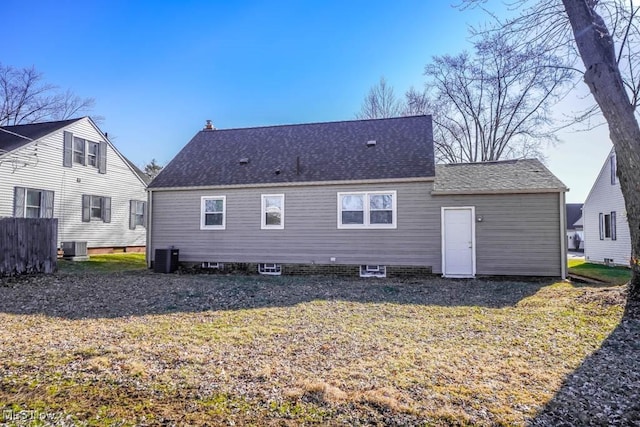 rear view of property with a lawn, cooling unit, and a shingled roof