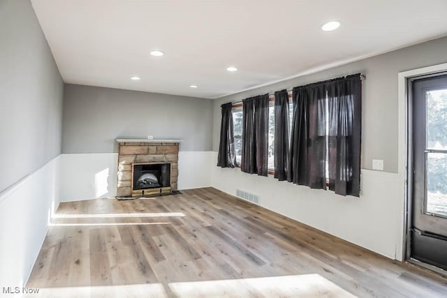 unfurnished living room with wood finished floors, recessed lighting, a fireplace, and visible vents