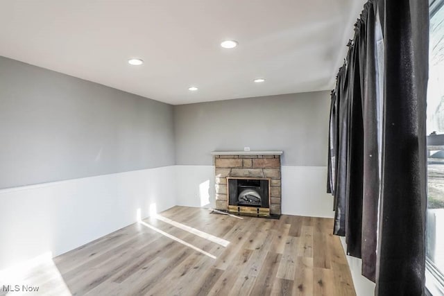 unfurnished living room featuring a stone fireplace, recessed lighting, and wood finished floors