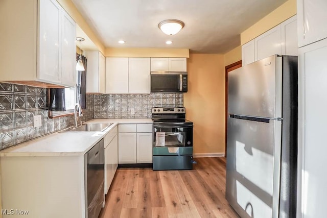 kitchen with light countertops, decorative backsplash, stainless steel appliances, white cabinetry, and a sink