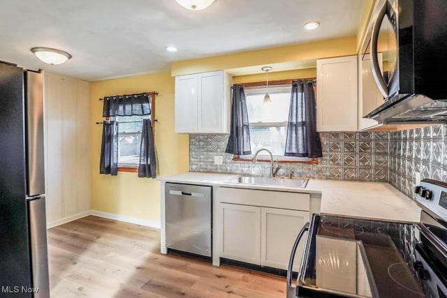 kitchen featuring baseboards, a sink, stainless steel appliances, light countertops, and light wood-style floors